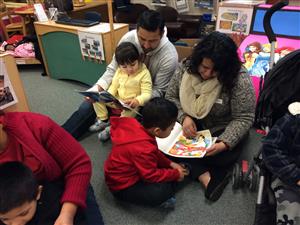 Mom, Dad, little girl in daddy's lap reading books 